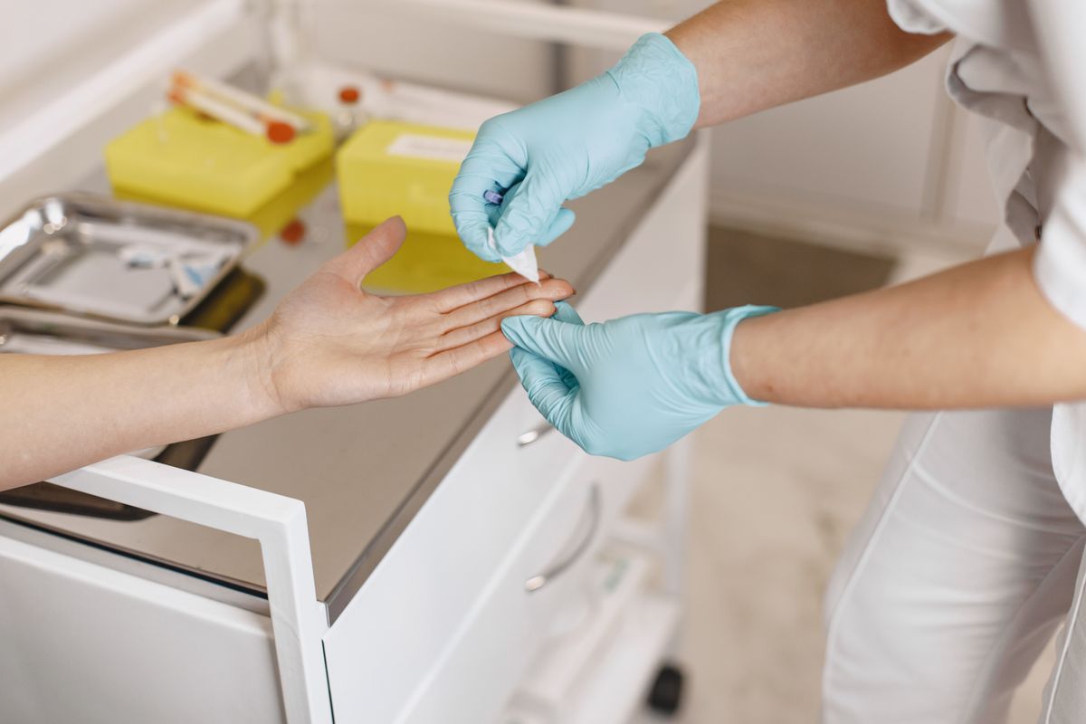 A gloved clinician treating a patient’s hand beside prepared clinical supplies